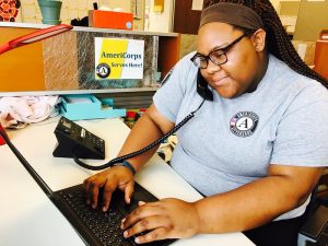 AmeriCorps members on the phone while typing on a laptop.